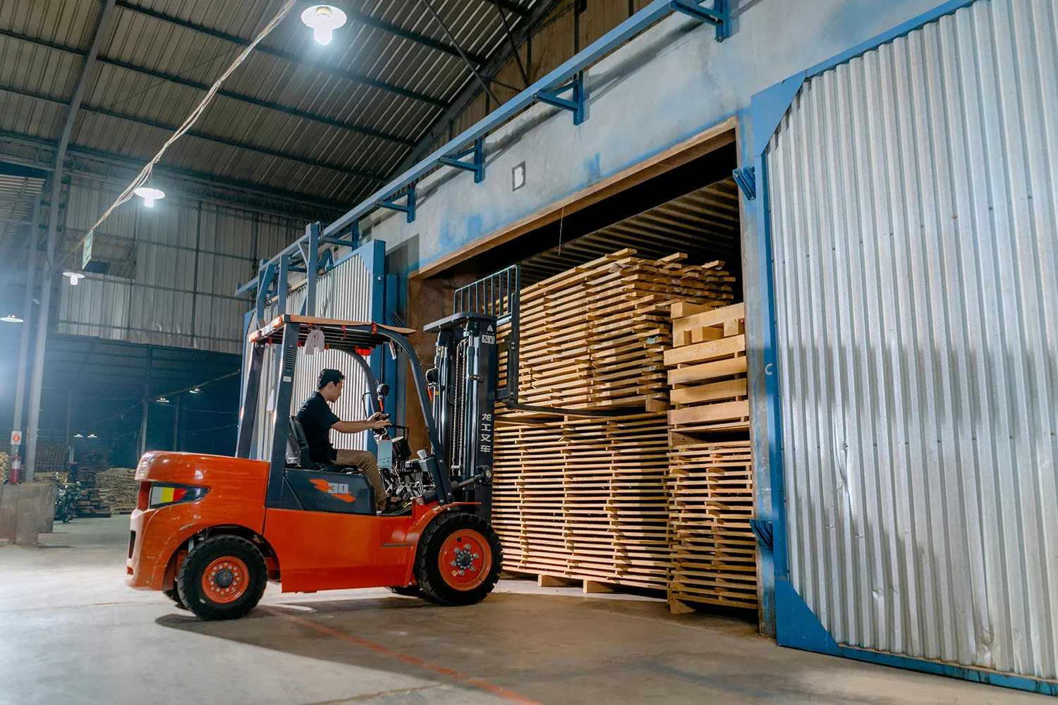 A forklift moving stacked timber in a warehouse