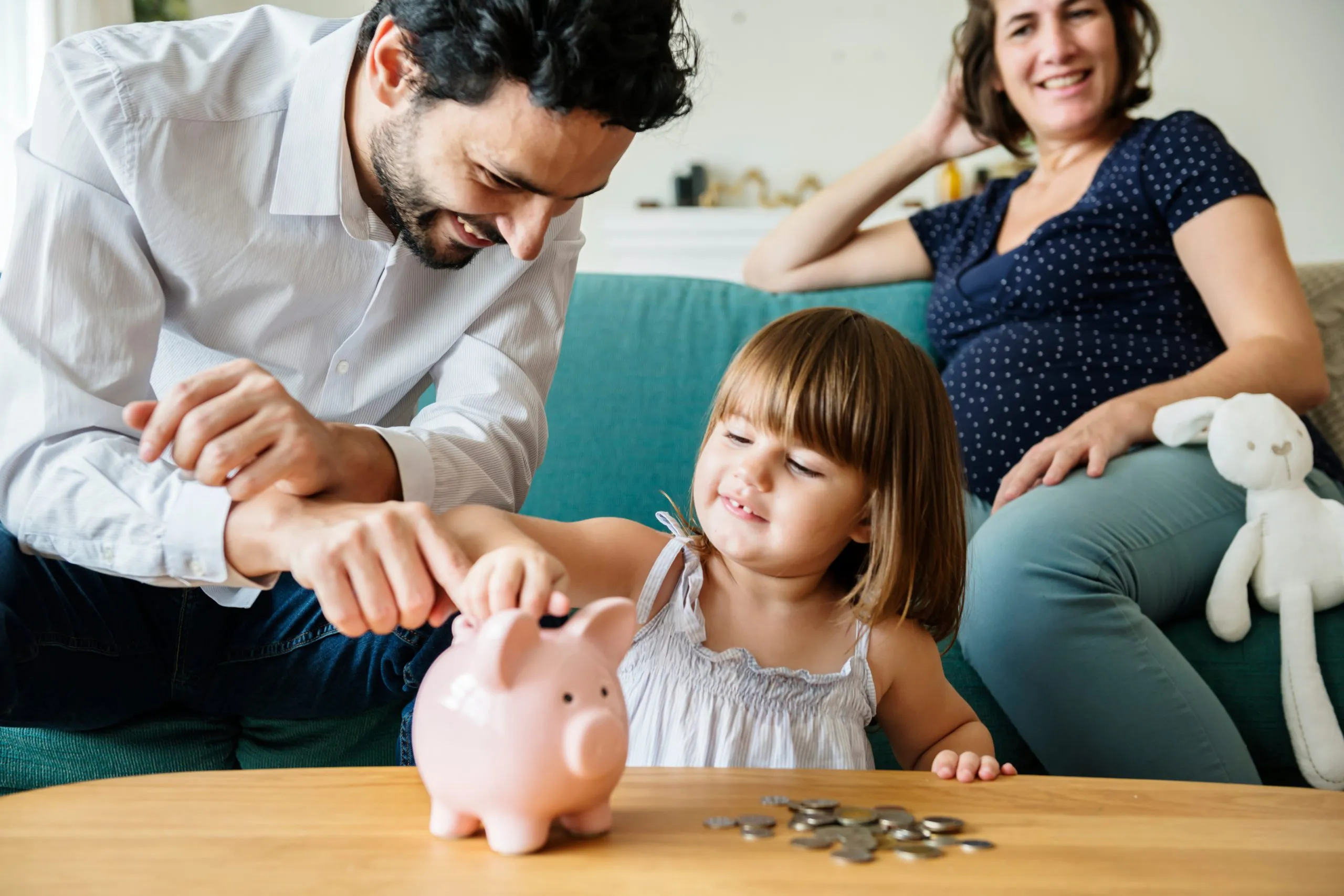 A father and daughter putting coins into a piggy bank at home